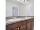 Bathroom with double sinks, brown cabinets, granite countertop and a large mirror at 3504 Kearsney Abbey Cir, Dover, FL 33527