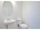 Simple half bathroom with a pedestal sink, toilet, and round mirror at 3504 Kearsney Abbey Cir, Dover, FL 33527