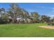 Large backyard featuring a well-maintained lawn, patio, and mature trees for shade at 4432 Huddlestone Dr, Wesley Chapel, FL 33545