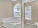 Bathroom featuring a soaking tub, tiled floors, and an arched window at 4432 Huddlestone Dr, Wesley Chapel, FL 33545