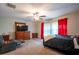Comfortable bedroom featuring a ceiling fan, dresser with mounted TV and red curtains adding a pop of color at 11910 Field Thistle Ct, Riverview, FL 33579