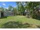 Large, private backyard with lush green grass, mature trees, and screened in pool at 621 Erin Way, Brooksville, FL 34601