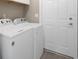 Bright laundry room featuring modern appliances, overhead cabinet and adjacent door at 621 Erin Way, Brooksville, FL 34601