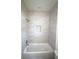 Modern bathroom with a tub, white and gray stone-look tile surround, and recessed lighting at 8990 Glenarm Way, Weeki Wachee, FL 34613