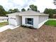A modern single-story home showcasing a side entry garage, a window with blue shutters, and fresh landscaping at 8990 Glenarm Way, Weeki Wachee, FL 34613