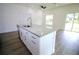 Bright kitchen showcases a large island with a granite countertop, stainless steel appliances and plank flooring at 8990 Glenarm Way, Weeki Wachee, FL 34613