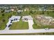 Aerial view showcasing a home with a paver driveway, lush lawn, and neighboring properties in a residential area at 235 Rotonda S Blvd, Rotonda West, FL 33947