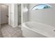 Bright main bathroom showcasing a garden tub, a tiled floor, and an arched window with natural light at 3403 30Th E Ln, Bradenton, FL 34208