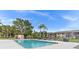 Community pool surrounded by lush trees, lounge chairs, and a grill, perfect for outdoor relaxation at 721 83Rd N Ave # 108, St Petersburg, FL 33702