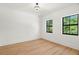 Well-lit bedroom with wood flooring, two windows, and neutral walls at 4115 N Central Ave, Tampa, FL 33603