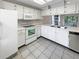 Bright kitchen featuring white cabinets and appliances, tiled floors, and ample counter space at 6902 Lakeview Ct, Tampa, FL 33634