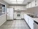 Well-lit kitchen with white appliances, ample counter space, and tiled flooring at 6902 Lakeview Ct, Tampa, FL 33634