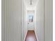 Narrow hallway featuring wood paneling and flooring leading to an exterior door at 75 Virginia Ct, Englewood, FL 34223