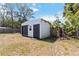 View of white storage shed with black doors, adjacent to a partially shaded fenced yard at 75 Virginia Ct, Englewood, FL 34223