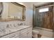 Bright bathroom with glass shower, white cabinets, marble countertops, and decorative mirror at 1966 Hyde Park St, Sarasota, FL 34239