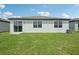 Backyard showcasing white exterior and a well-maintained lawn under a sunny sky at 7740 Gilchrist Springs Dr, Parrish, FL 34219