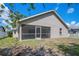 A view of the home's beige exterior, screened-in porch, and ample backyard, partially shaded by trees at 5009 72Nd E Ct, Bradenton, FL 34203