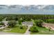Aerial view of a yellow house surrounded by lush greenery, mature trees, and a well-maintained landscape at 9475 Dunkirk Rd, Spring Hill, FL 34608