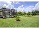 Expansive backyard with lush green grass and pool view with a screened in enclosure at 9475 Dunkirk Rd, Spring Hill, FL 34608