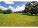 Expansive backyard with lush green grass, mature trees, and the home's exterior in the distance at 9475 Dunkirk Rd, Spring Hill, FL 34608