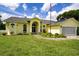 Charming yellow home featuring well-manicured lawn, beautiful front garden, and an American flag at 9475 Dunkirk Rd, Spring Hill, FL 34608