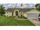 Charming yellow home featuring well-manicured lawn, beautiful front garden, and an American flag at 9475 Dunkirk Rd, Spring Hill, FL 34608