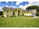 Charming yellow home with manicured lawn, arched entryway, and American flag at 9475 Dunkirk Rd, Spring Hill, FL 34608