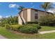 Apartment building featuring mature landscaping, steps to upper units, blue skies, and palm trees at 2597 Countryside Blvd # 204, Clearwater, FL 33761