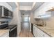 Galley kitchen with white cabinets and granite countertops, with a view to the living room at 2597 Countryside Blvd # 204, Clearwater, FL 33761