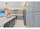 Modern kitchen featuring gray cabinets, a stainless steel refrigerator, and a marble countertop island with gold fixtures at 3061 Hollow Hickory Pl, Wesley Chapel, FL 33543