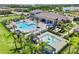 Aerial view of a resort-style pool and splash pad area surrounded by palm trees and lounge chairs at 3061 Hollow Hickory Pl, Wesley Chapel, FL 33543