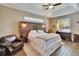 Spacious bedroom featuring a rustic wood headboard, tray ceiling, wood-look floors, and a leather chair at 12802 Cattail Shore Ln, Riverview, FL 33579