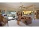 Cozy living room featuring a ceiling fan, sliding glass doors to the pool, and convenient kitchen access at 268 Cory St, Port Charlotte, FL 33953