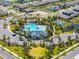 Aerial view of community amenities featuring a resort-style pool, tennis courts, playground, and ample parking at 1220 Tahitian Sunrise Dr, Plant City, FL 33565