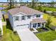 Aerial view of a gray two-story home with a manicured lawn, covered porch, and an adjacent pond at 1220 Tahitian Sunrise Dr, Plant City, FL 33565