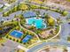 Aerial view featuring pool, clubhouse, basketball and tennis courts, playground, green spaces, and sidewalks at 1220 Tahitian Sunrise Dr, Plant City, FL 33565