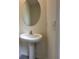 Bright powder room featuring a pedestal sink, round mirror and neutral color palette at 1570 Hubbell Rd, Wesley Chapel, FL 33543