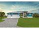 Beautiful home featuring a three-car garage, elegant gray brick driveway, and lush green lawn at 205 Rotonda S Blvd, Rotonda West, FL 33947
