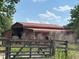 Exterior shot of a red barn with a metal roof and metal gate at 23046 Brandy Rd, Land O Lakes, FL 34639