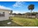 Lush backyard with a white pergola-covered patio, palm trees, and a serene, fenced-in area at 4043 Topsail Trl, New Port Richey, FL 34652