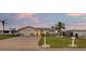 Lovely single-story home with a paved driveway, well-maintained lawn, and tropical landscaping at sunset at 4043 Topsail Trl, New Port Richey, FL 34652