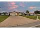 Inviting single-story home featuring a paved driveway, green lawn, and mature landscaping at dusk at 4043 Topsail Trl, New Port Richey, FL 34652