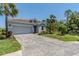 Paver driveway leading to a gray home with a tile roof and mature landscaping at 507 Daylily Blvd, Nokomis, FL 34275
