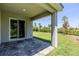 Covered patio with stone flooring overlooking the manicured lawn at 507 Daylily Blvd, Nokomis, FL 34275