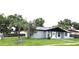 Exterior view of a grey house with well-kept landscaping, mature trees, and a grey roof at 2202 Whitney Pl, Valrico, FL 33594