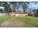 Spacious backyard with lush green grass, a patio, and an orange brick home under a blue sky at 3716 Mistwood Dr, Tampa, FL 33619