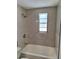 Modern bathroom featuring gray tiled walls, a shower, and a window providing natural light at 3716 Mistwood Dr, Tampa, FL 33619