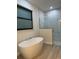 Bathroom features standalone soaking tub, tile floors, and walk-in shower with marble-look tile at 20296 Rutherford Ave, Port Charlotte, FL 33952
