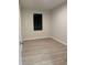 A bedroom with light wood-look floors, a window, and neutral walls create a calm atmosphere at 20296 Rutherford Ave, Port Charlotte, FL 33952