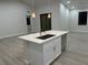 Stylish kitchen island with quartz countertop and stainless steel sink, complemented by wood-look tile flooring at 20296 Rutherford Ave, Port Charlotte, FL 33952